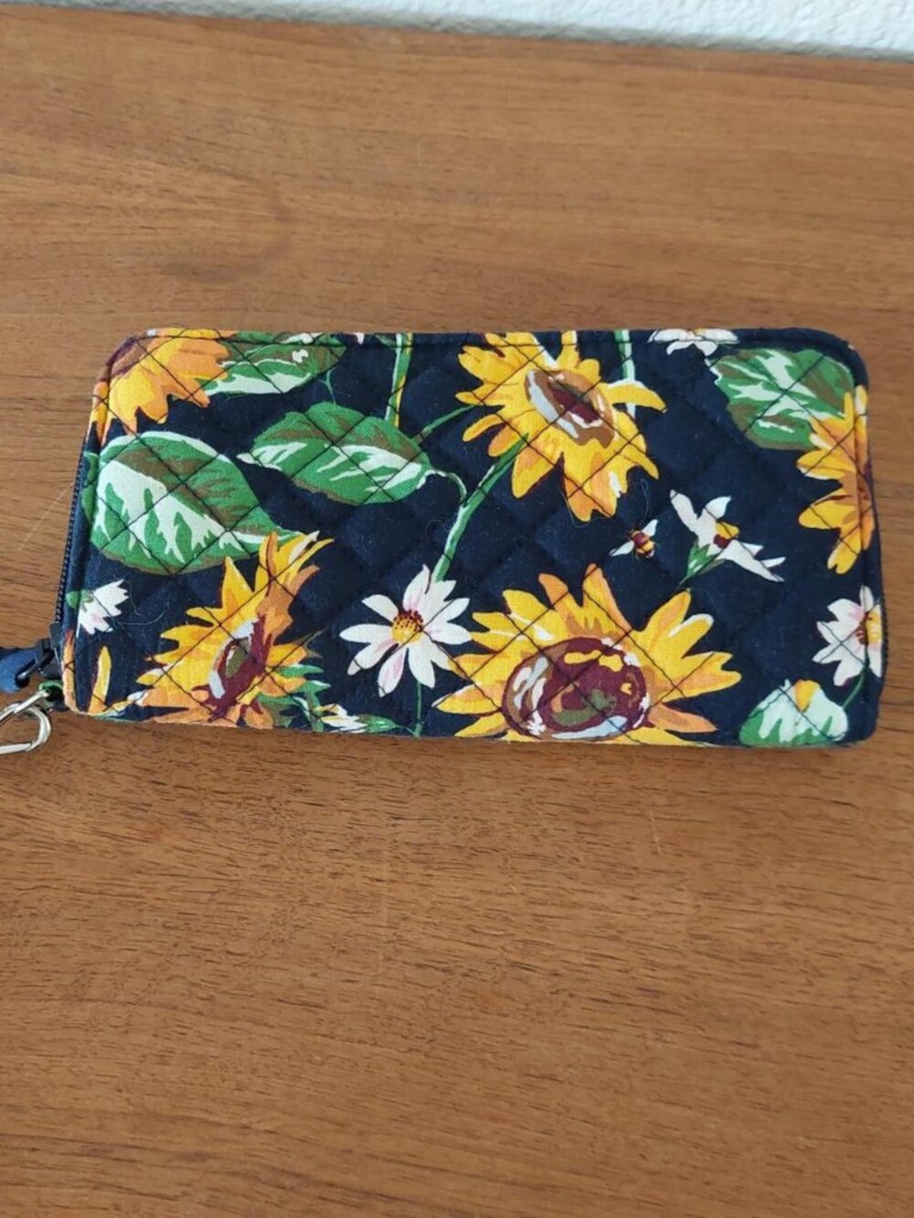 Vera Bradley Sunflower Wristlet with yellow sunflowers and white daisies on a da